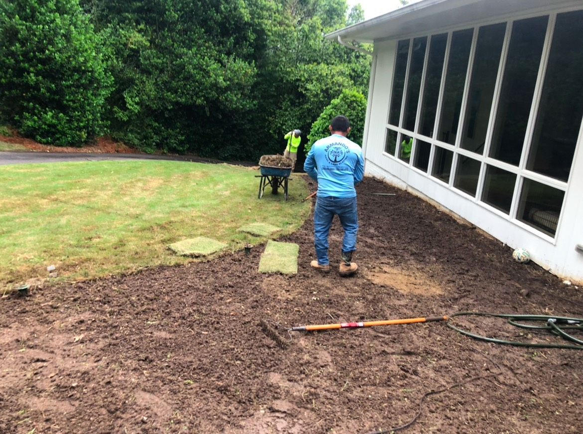 A man is standing in the dirt in front of a house.