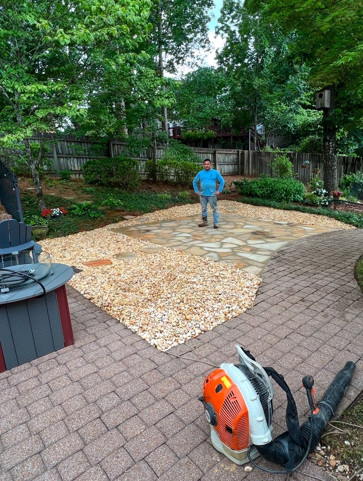 A man is standing on a brick patio next to a blower.