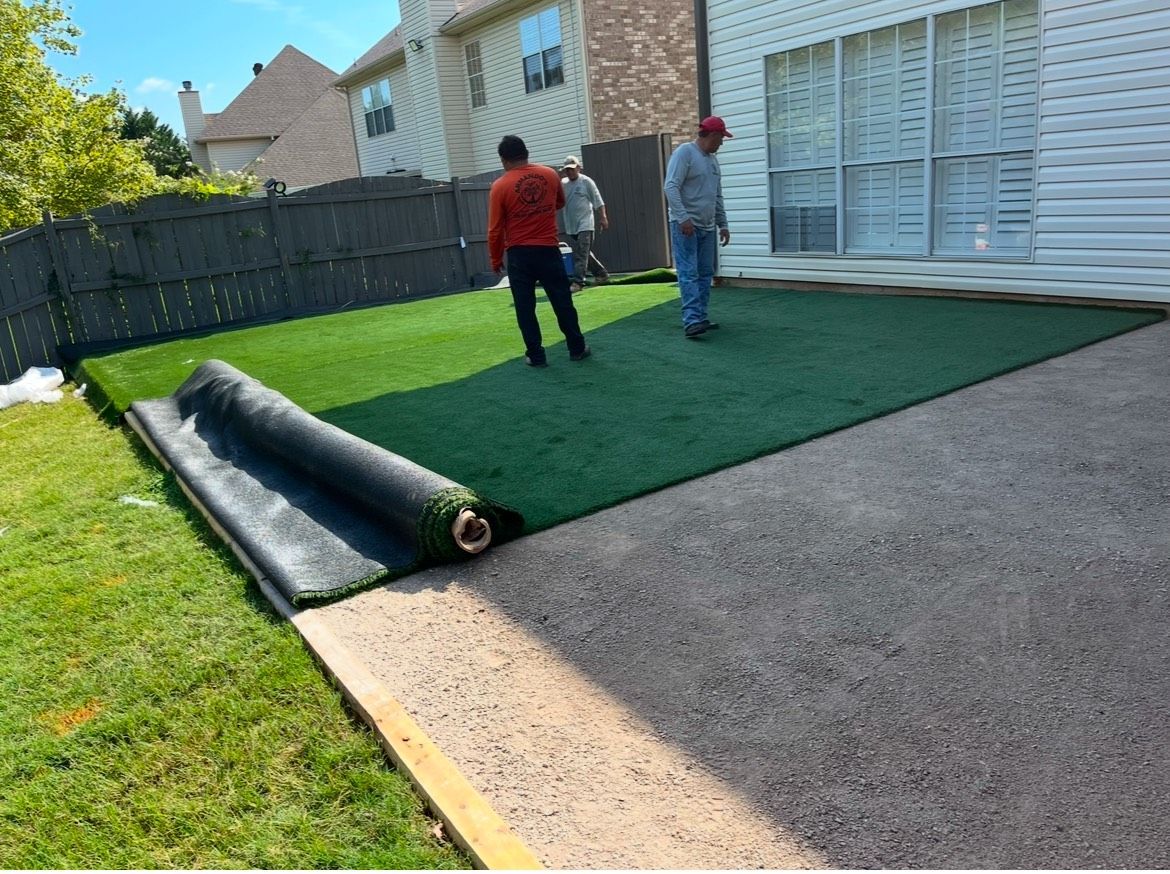 A group of men are installing artificial grass in a backyard.