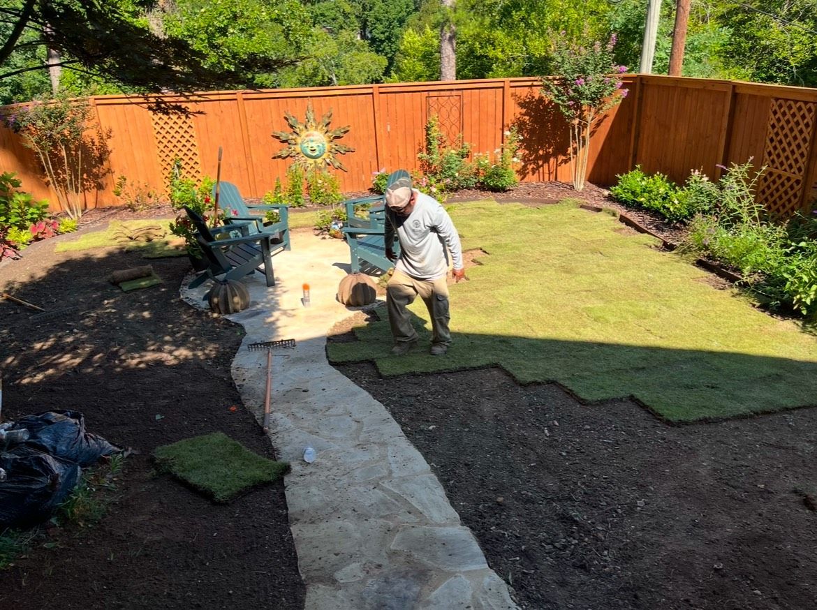 A man is working on a lawn in a backyard.