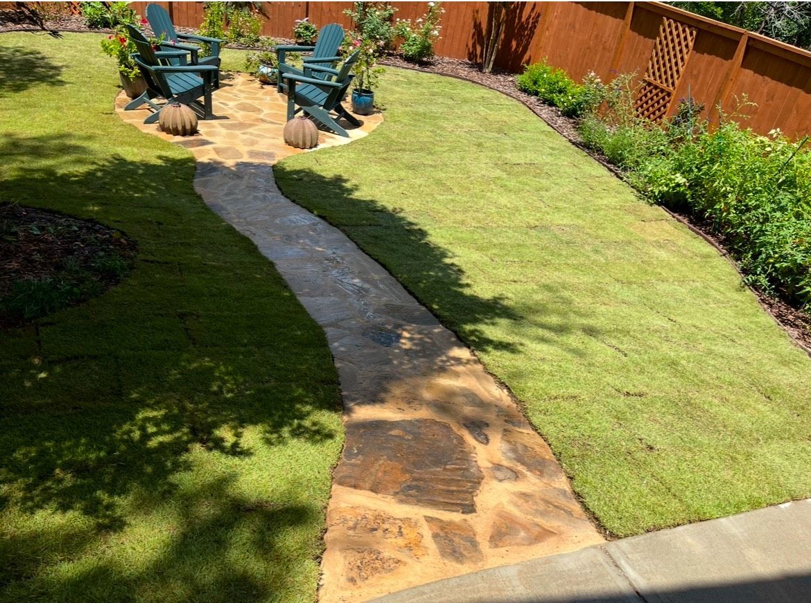 A stone walkway leading to a patio in a backyard.