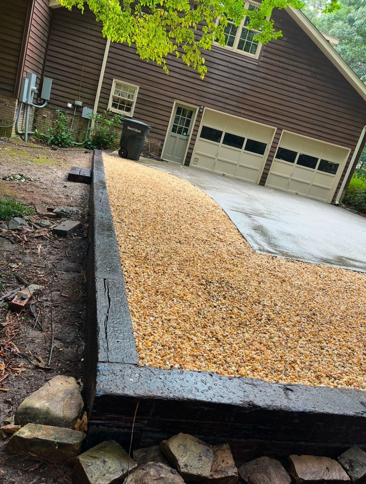 A driveway with gravel and rocks in front of a house.