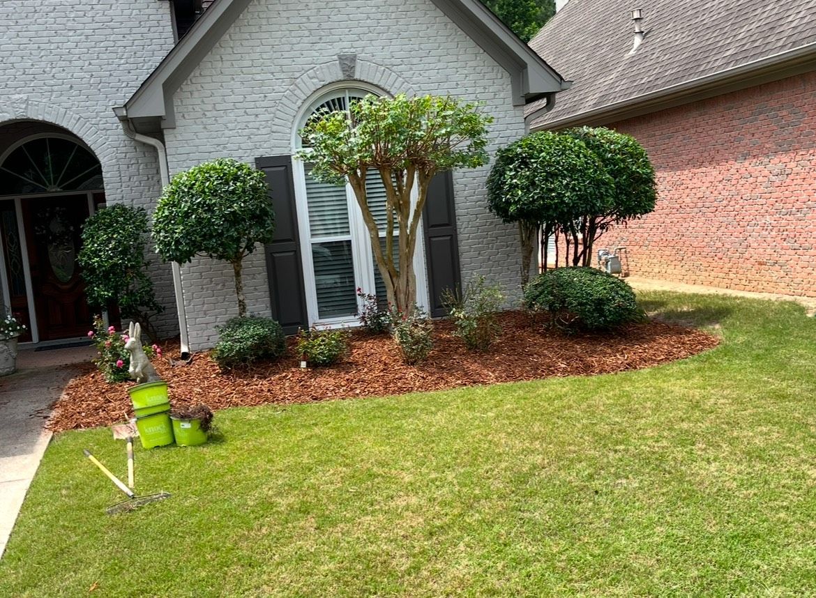 A white brick house with a lush green lawn in front of it.