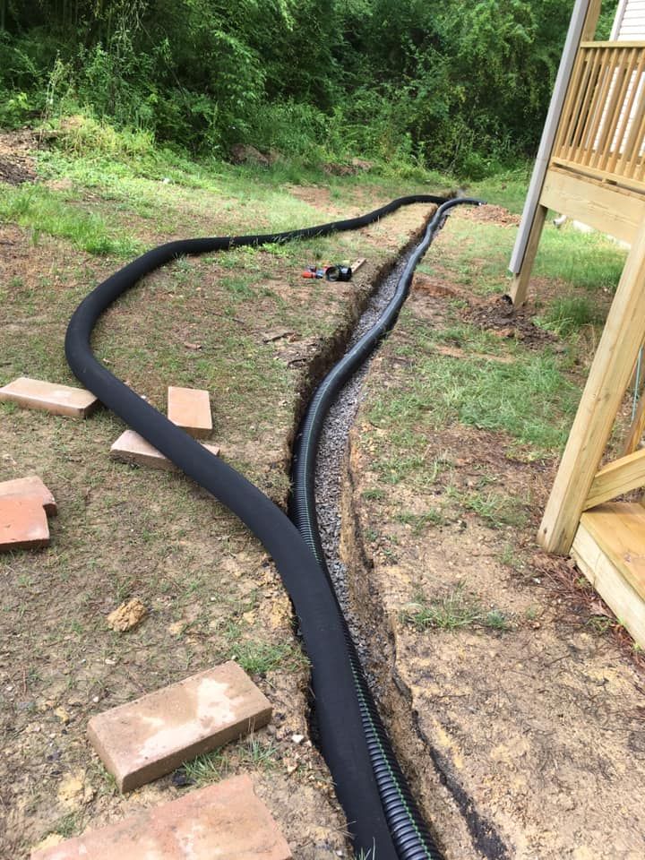 A drain pipe is being installed in a backyard next to a deck.