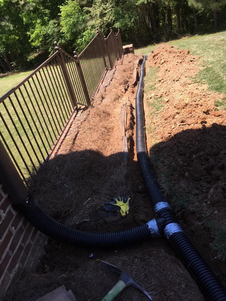 A hose is laying in the dirt next to a fence