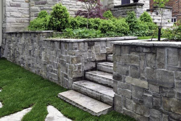 A stone wall with stairs leading up to a house.