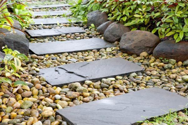 A stone walkway in a garden surrounded by rocks and plants.