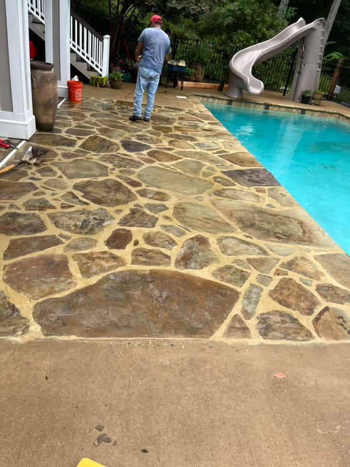 A man is standing on a stone patio next to a pool with a slide.