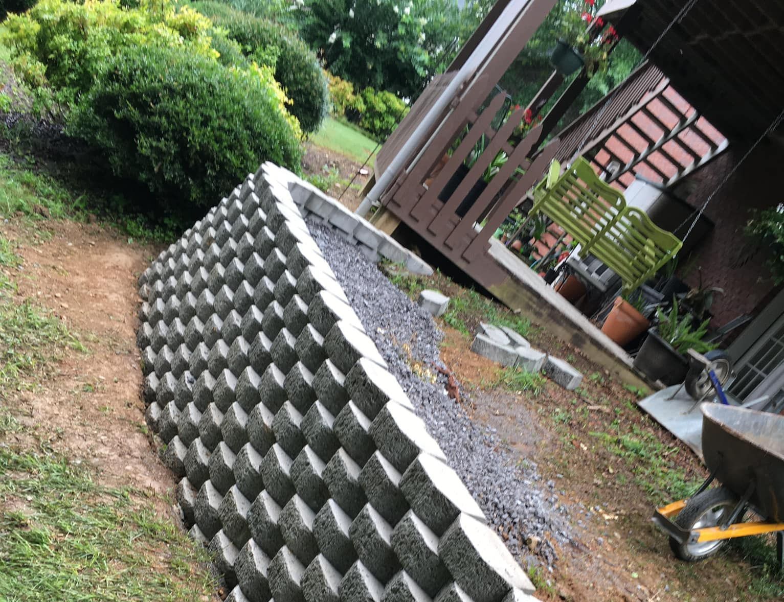 A concrete wall is being built in a yard next to a porch.