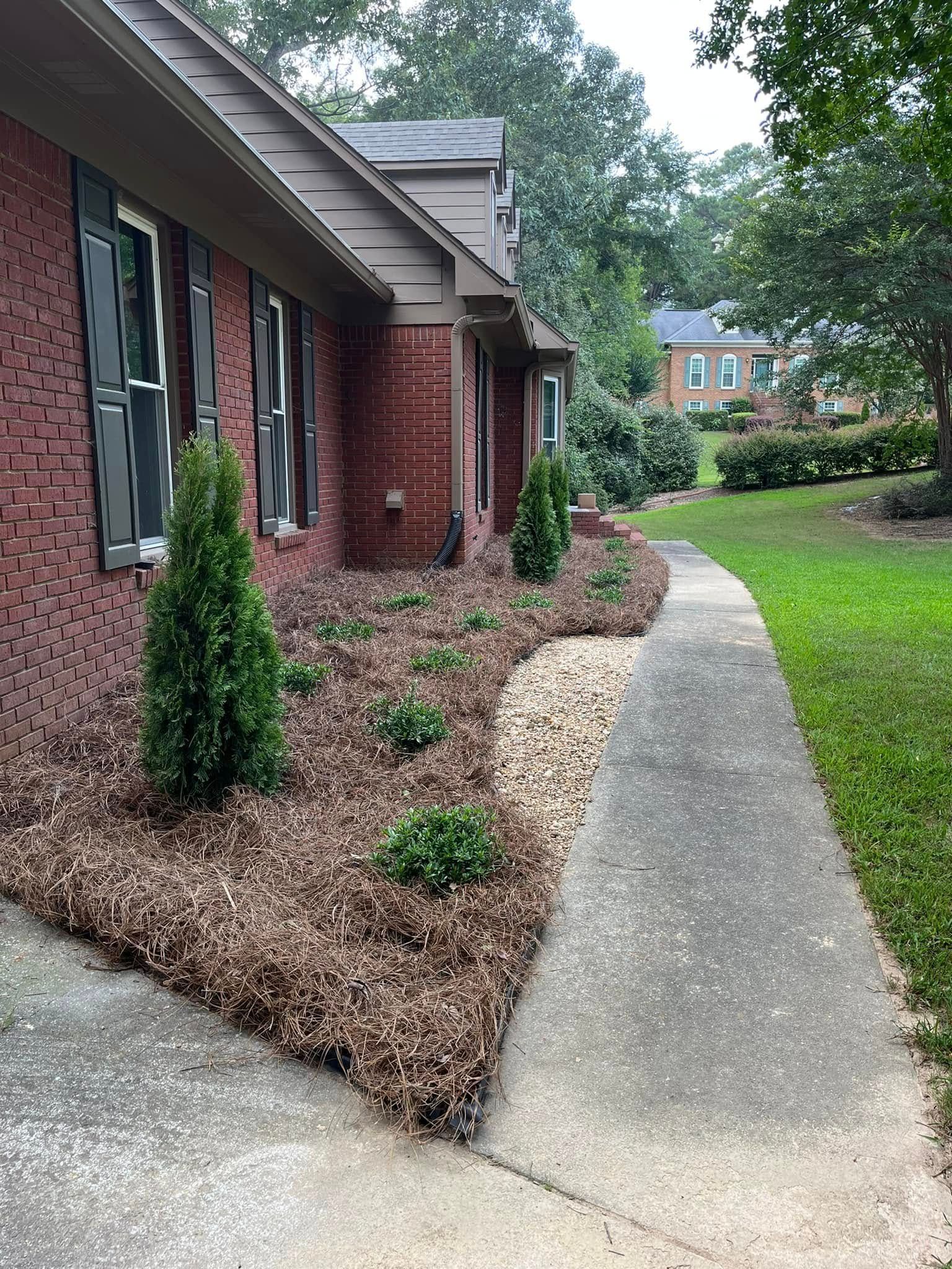 A brick house with a concrete walkway leading to it.