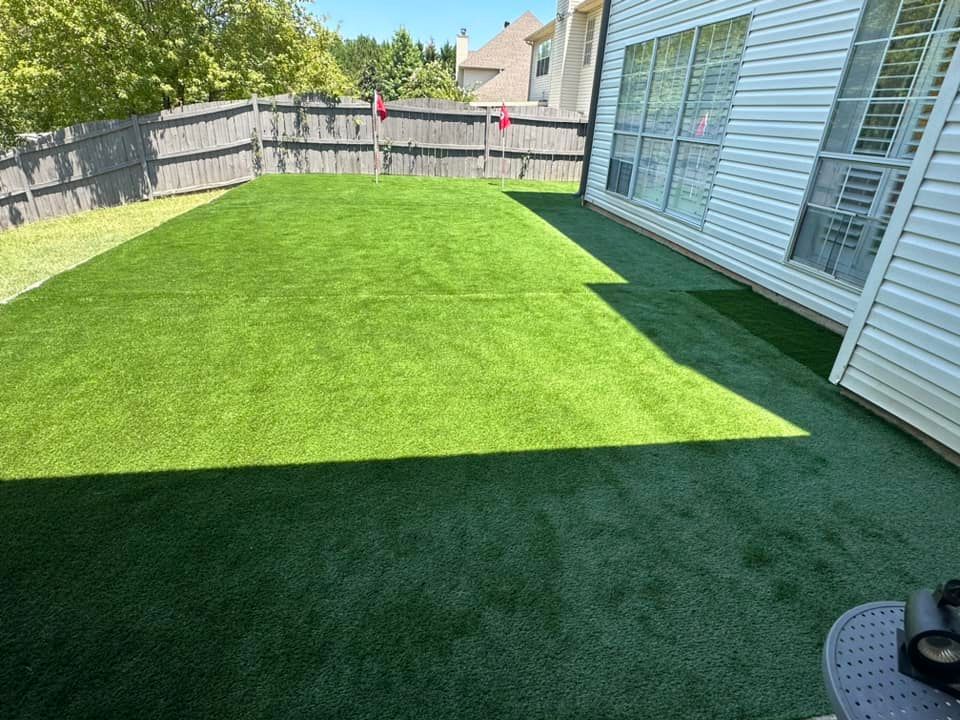 There is a putting green in the backyard of a house.