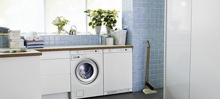 white dryer in laundry room with blue tiles