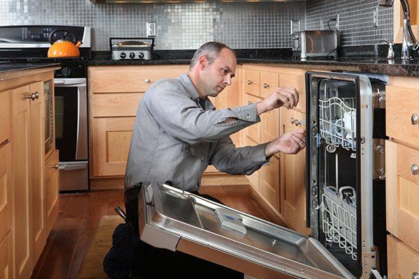 repairman working on dishwasher