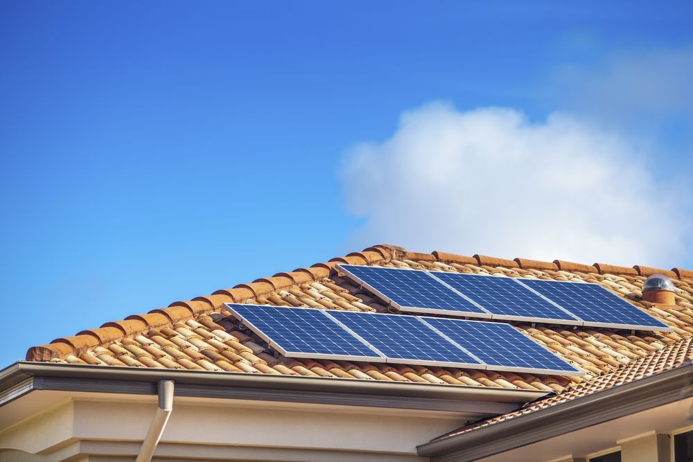 Solar Panels on a Terracotta Tile Roof Against a Blue Sky — NTR Electrical In Toogoom, QLD