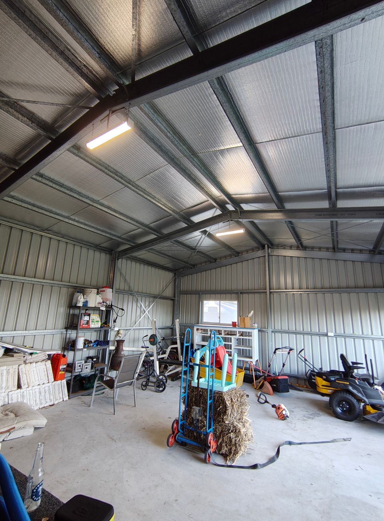 Interior View of a Metal Shed With Storage, Work Out Equipment, and Lawn Care Tools — NTR Electrical In Maryborough, QLD