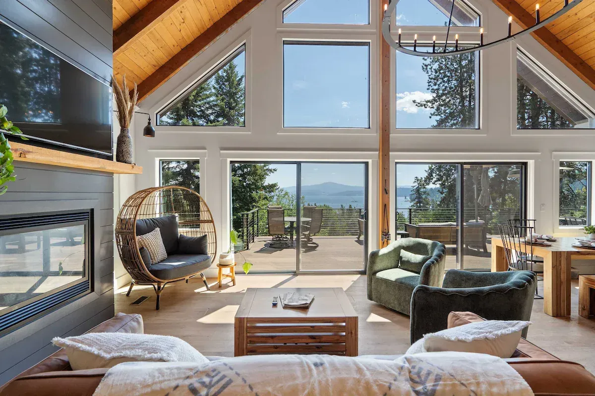 Living room with large windows, fireplace, and seating; mountain view on Lake Coeur d'Alene.