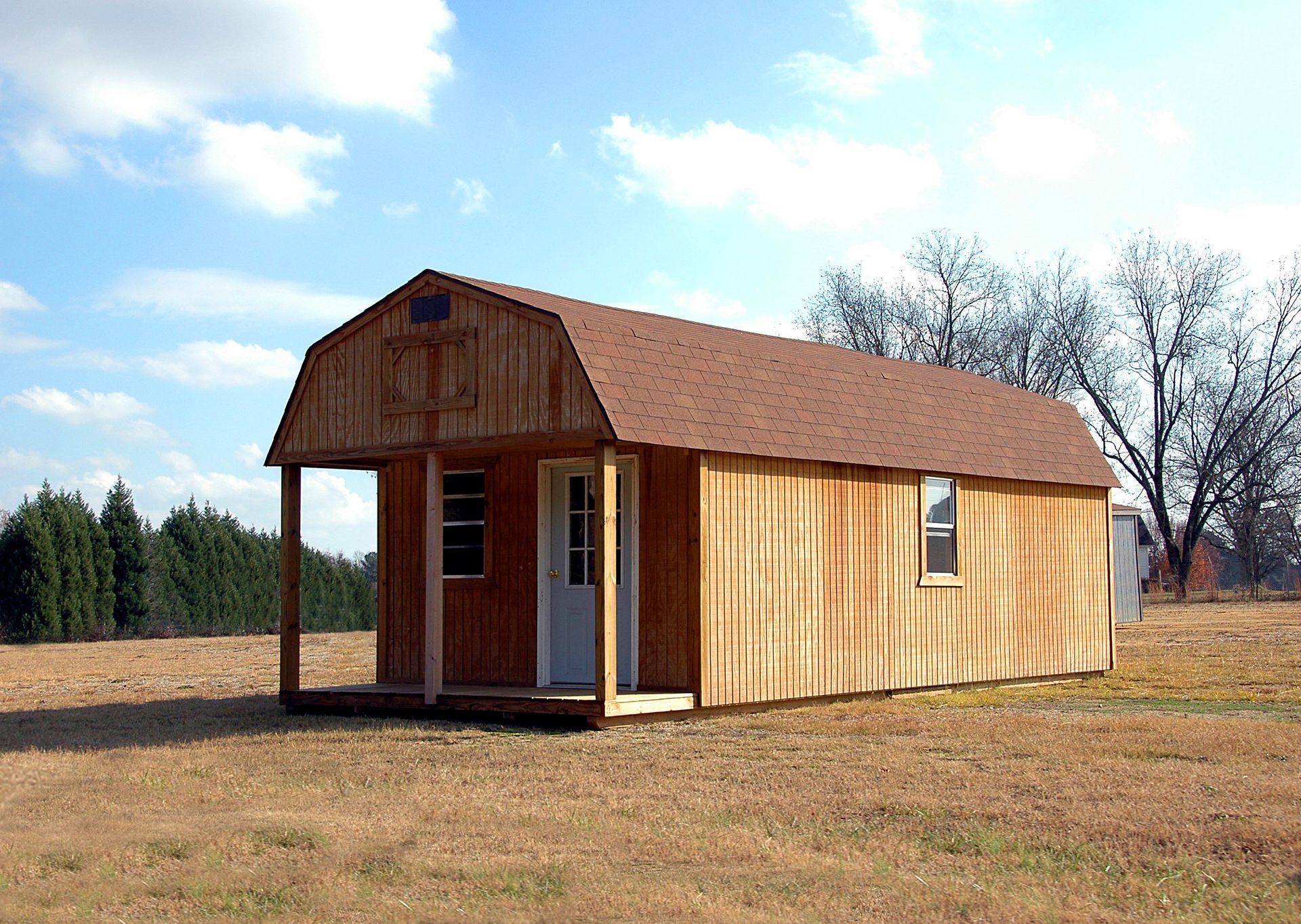 a small wooden house with a porch is sitting in the middle of a field