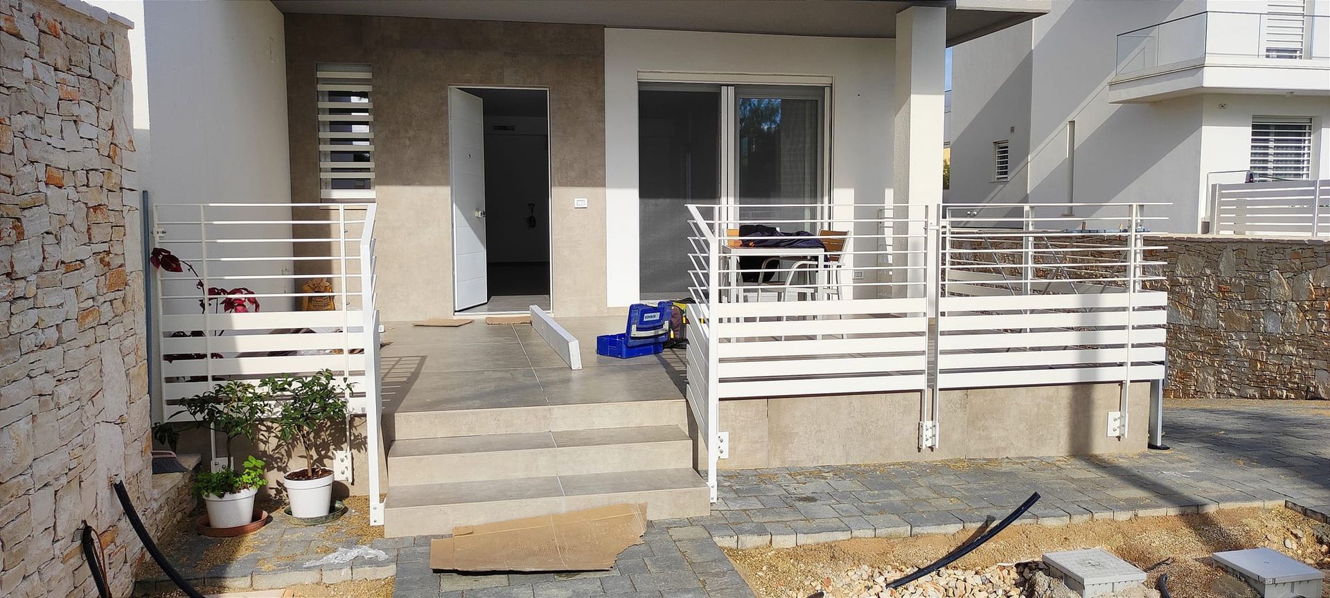 L'esterno di una casa con ringhiera bianca e gradini che conducono a una porta e a una porta scorrevole in vetro.