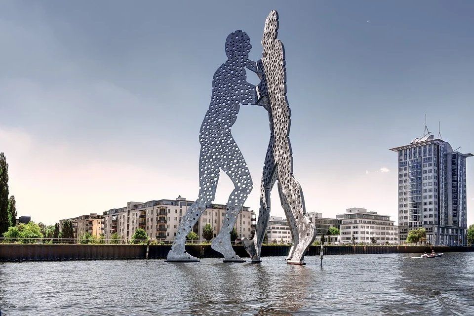 Eine Statue von zwei Menschen, die nebeneinander vor einem Gewässer stehen