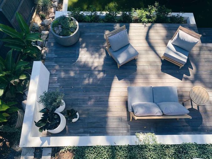 Wooden Patio with chairs in the center and plants surrounding it