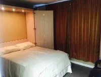 A bedroom with a bed , nightstand , lamp and mattress.