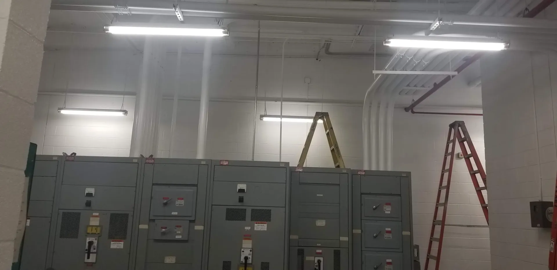 A room with a lot of electrical panels and a ladder.