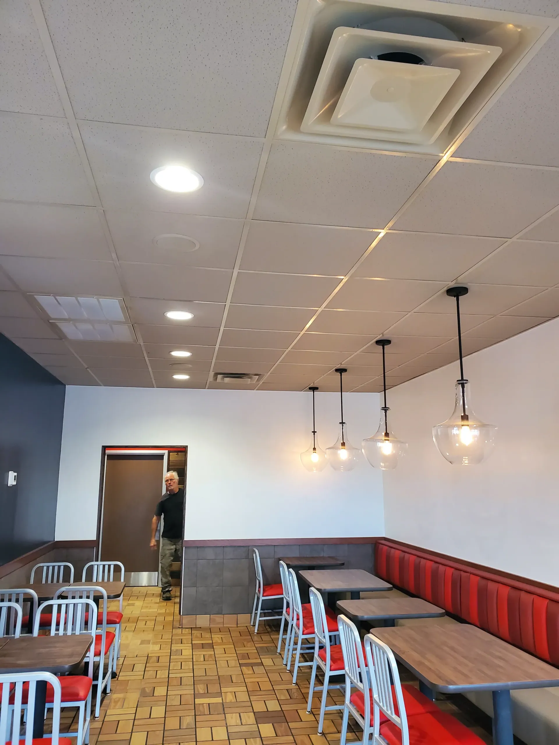 A restaurant with tables and chairs and a man standing in the doorway
