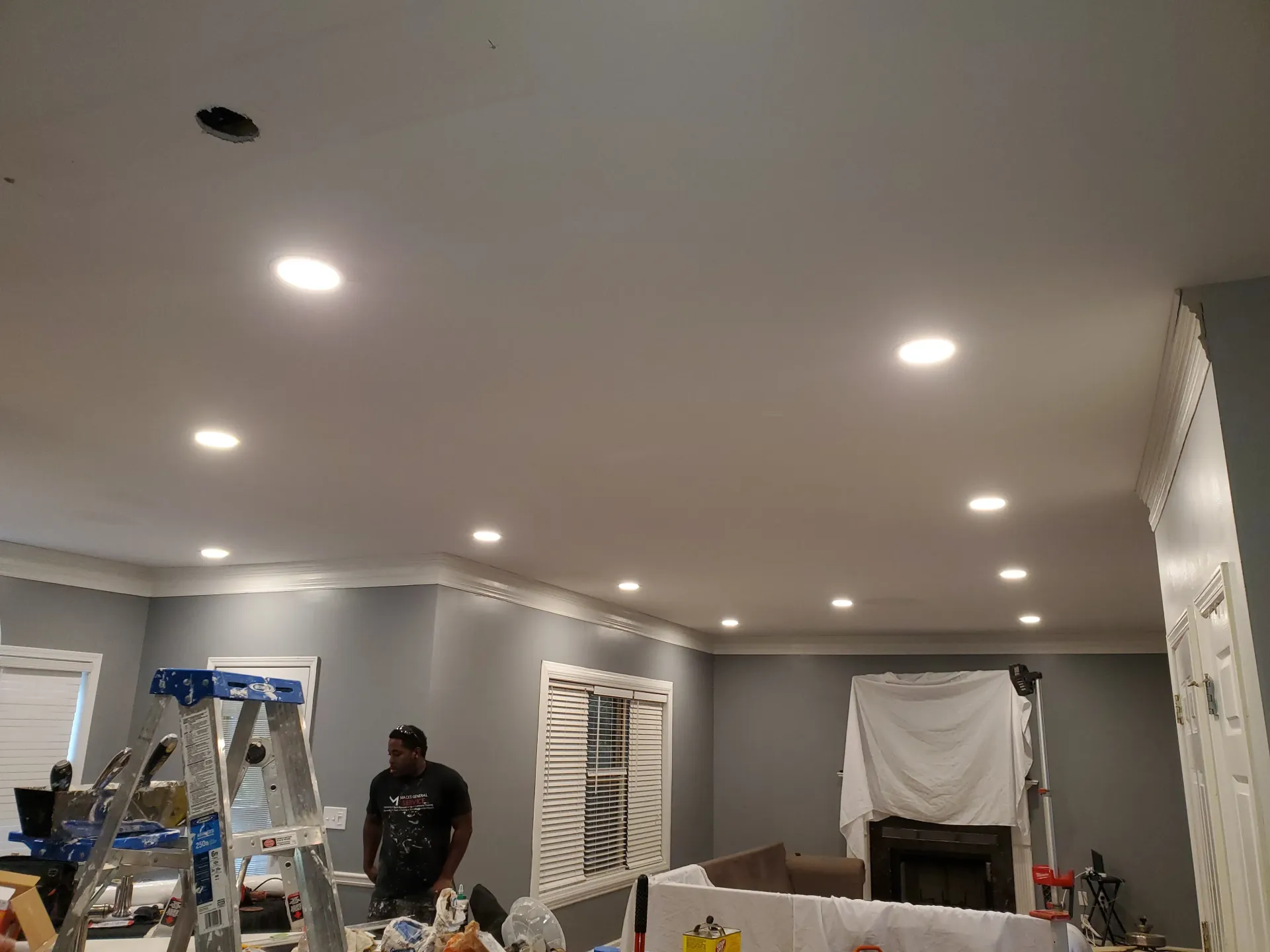 A man is standing next to a ladder in a living room.