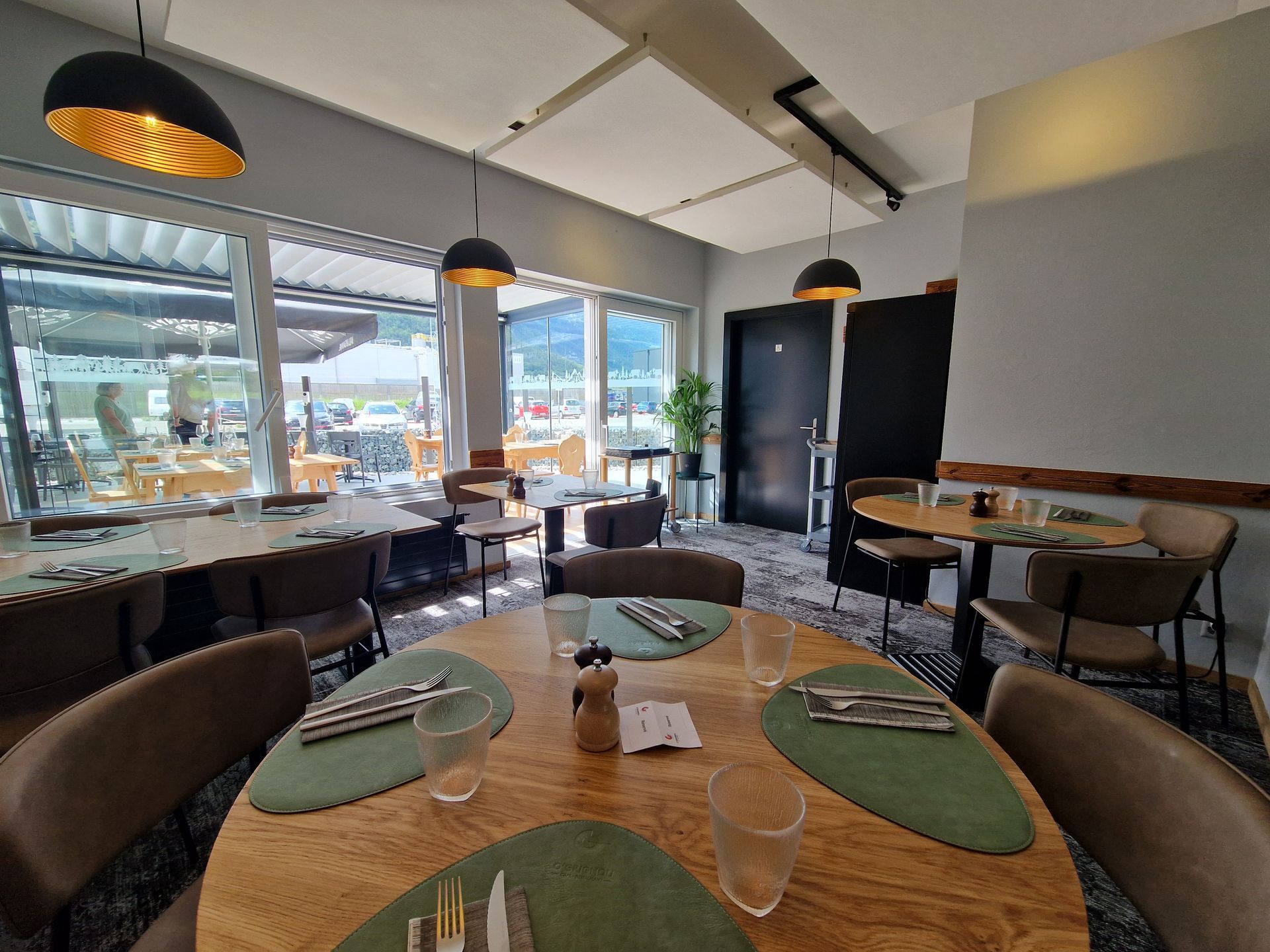 Un restaurant avec des tables, des chaises et des ustensiles dessus.