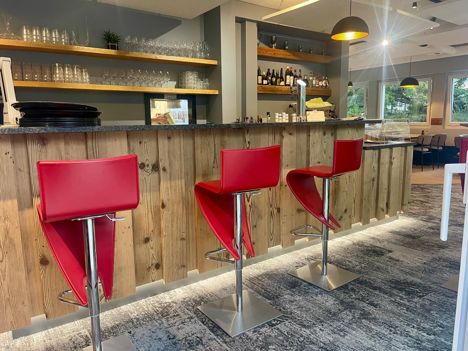 Un bar avec des chaises rouges et un comptoir en bois dans un restaurant.