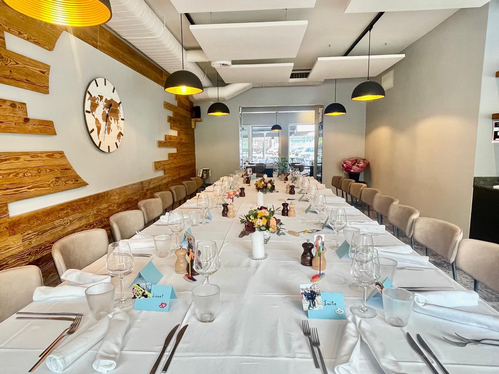 Une longue table dans un restaurant avec une horloge au mur.