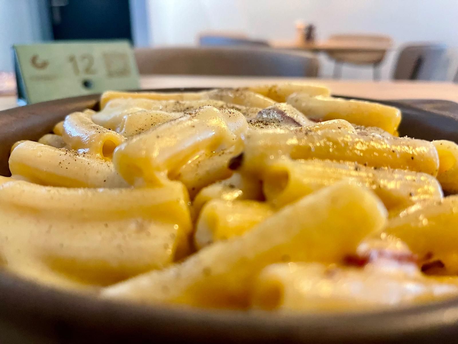 Un gros plan d'une assiette de pâtes avec sauce et champignons sur une table.