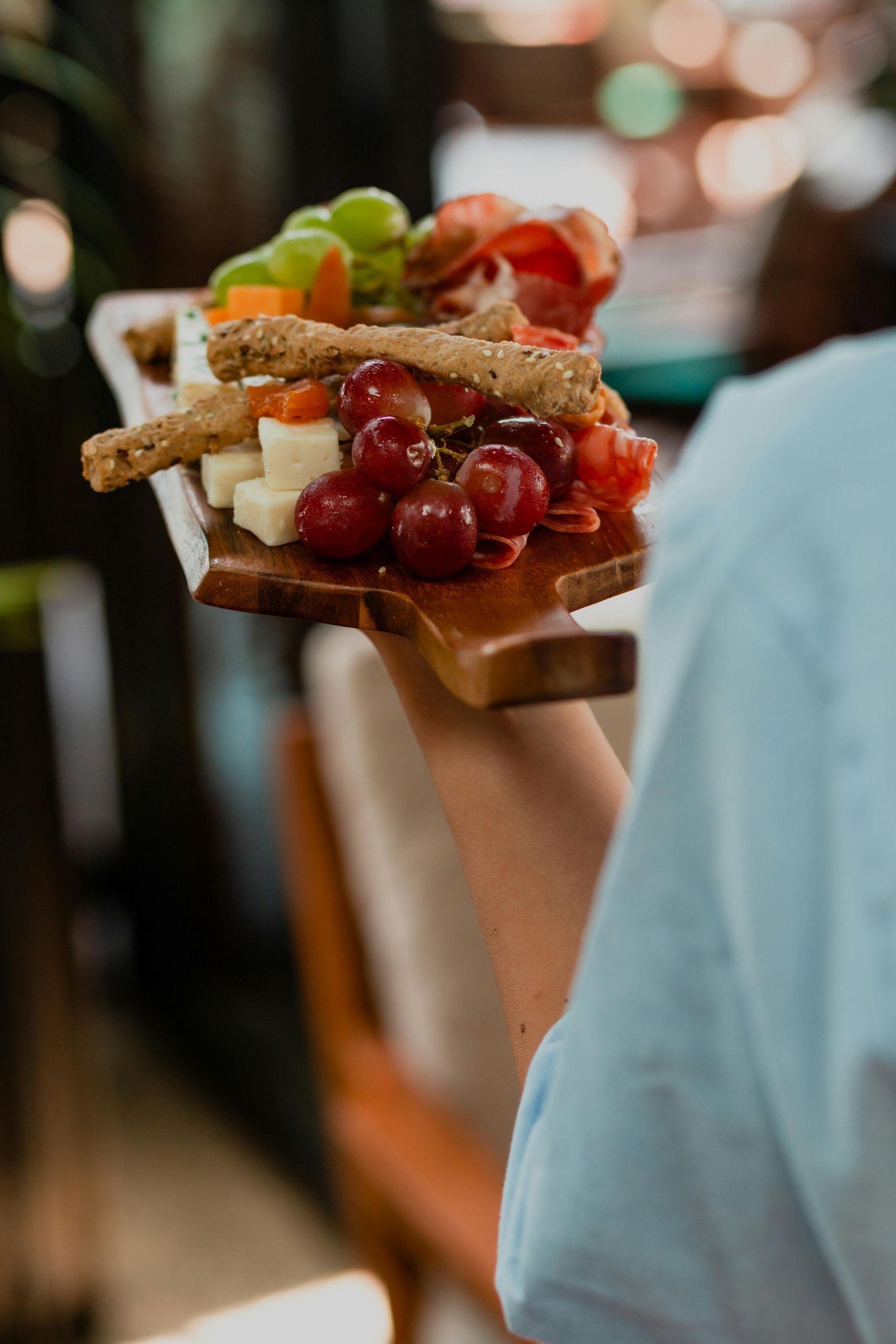 Une personne tient un plateau de nourriture sur une planche à découper en bois.