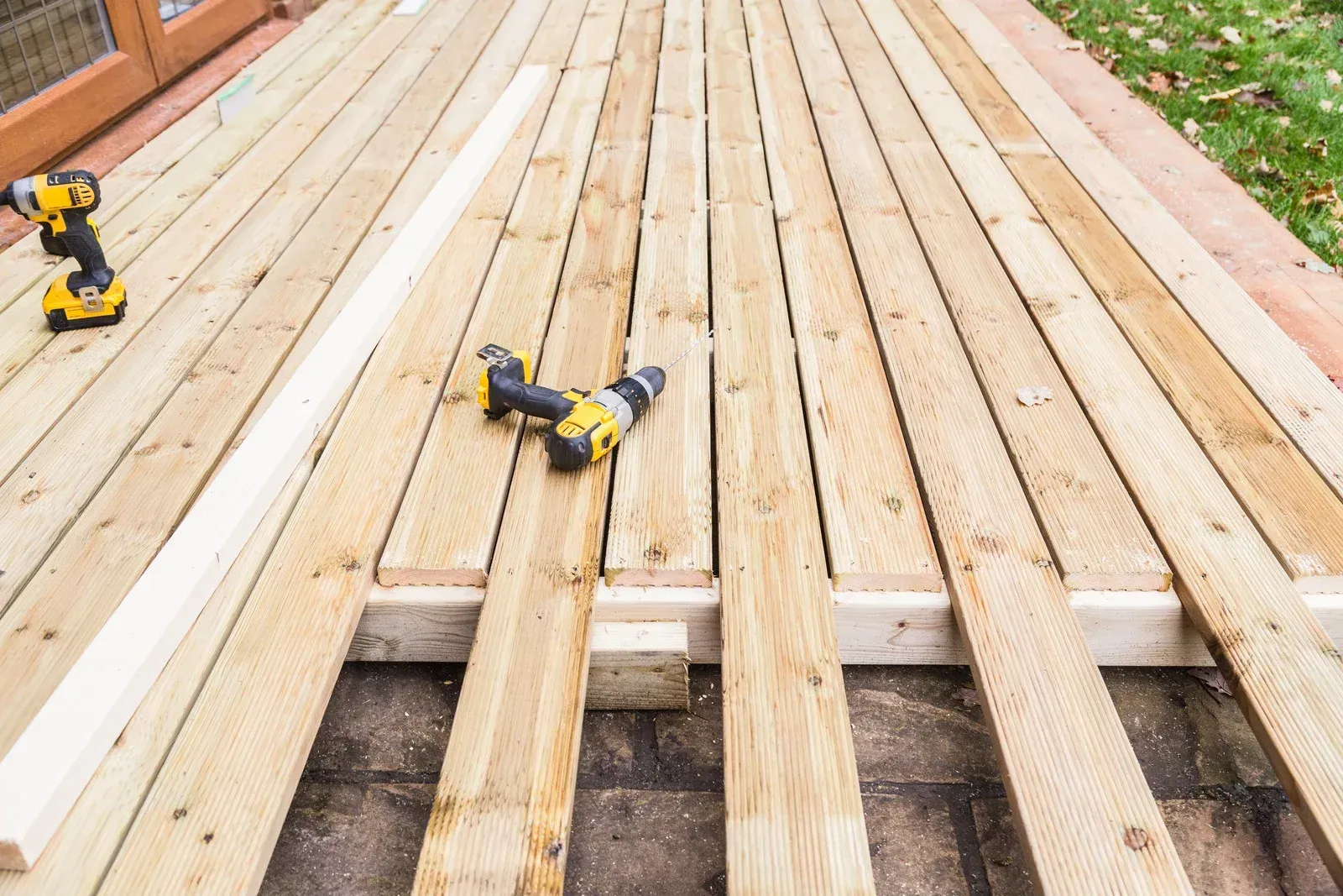 Two drills are sitting on top of a wooden deck.