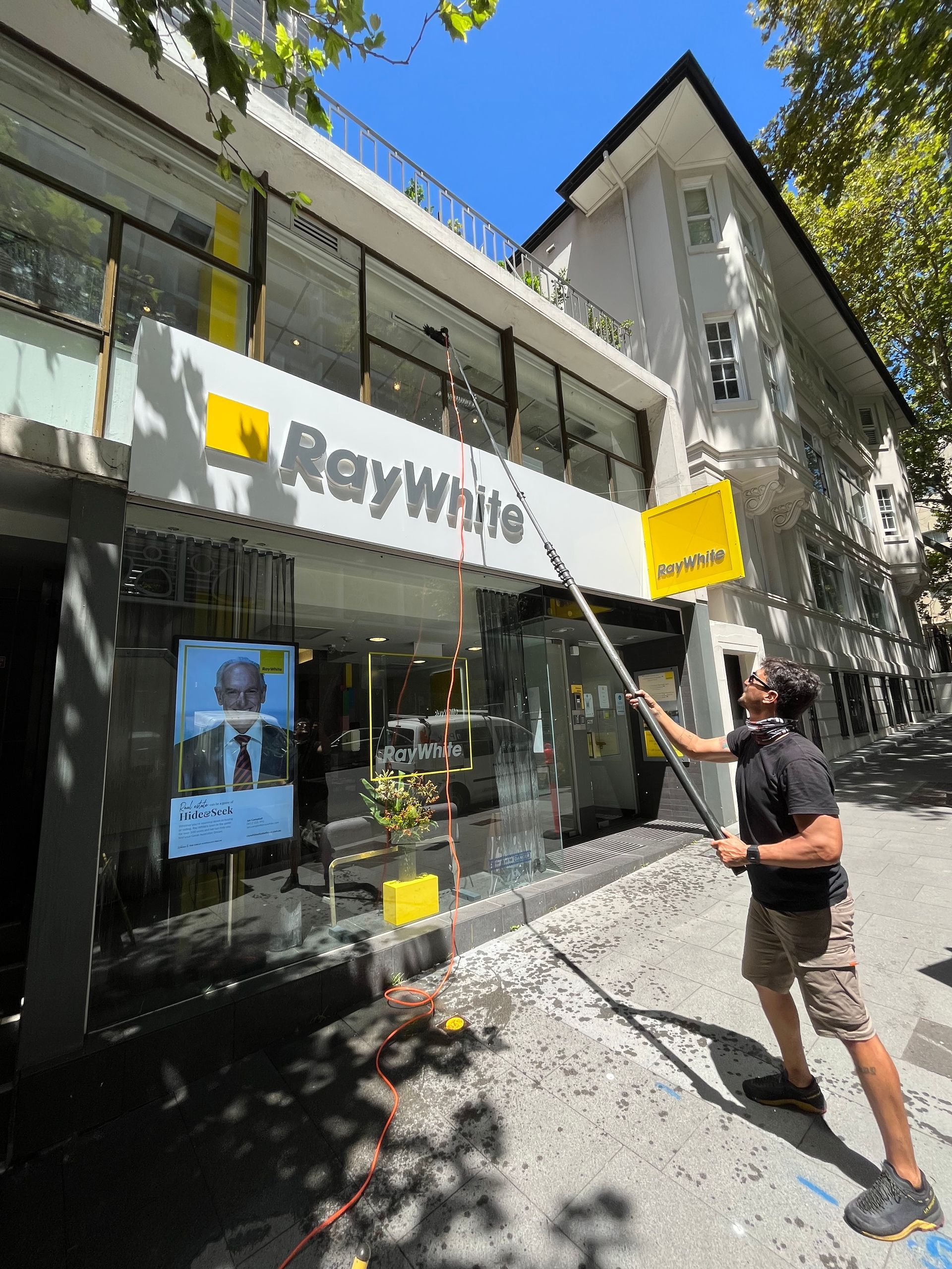 A Man Is Rappelling Through The Air Above A Building — Freshwater Exterior Cleaning in Lennox Head, NSW