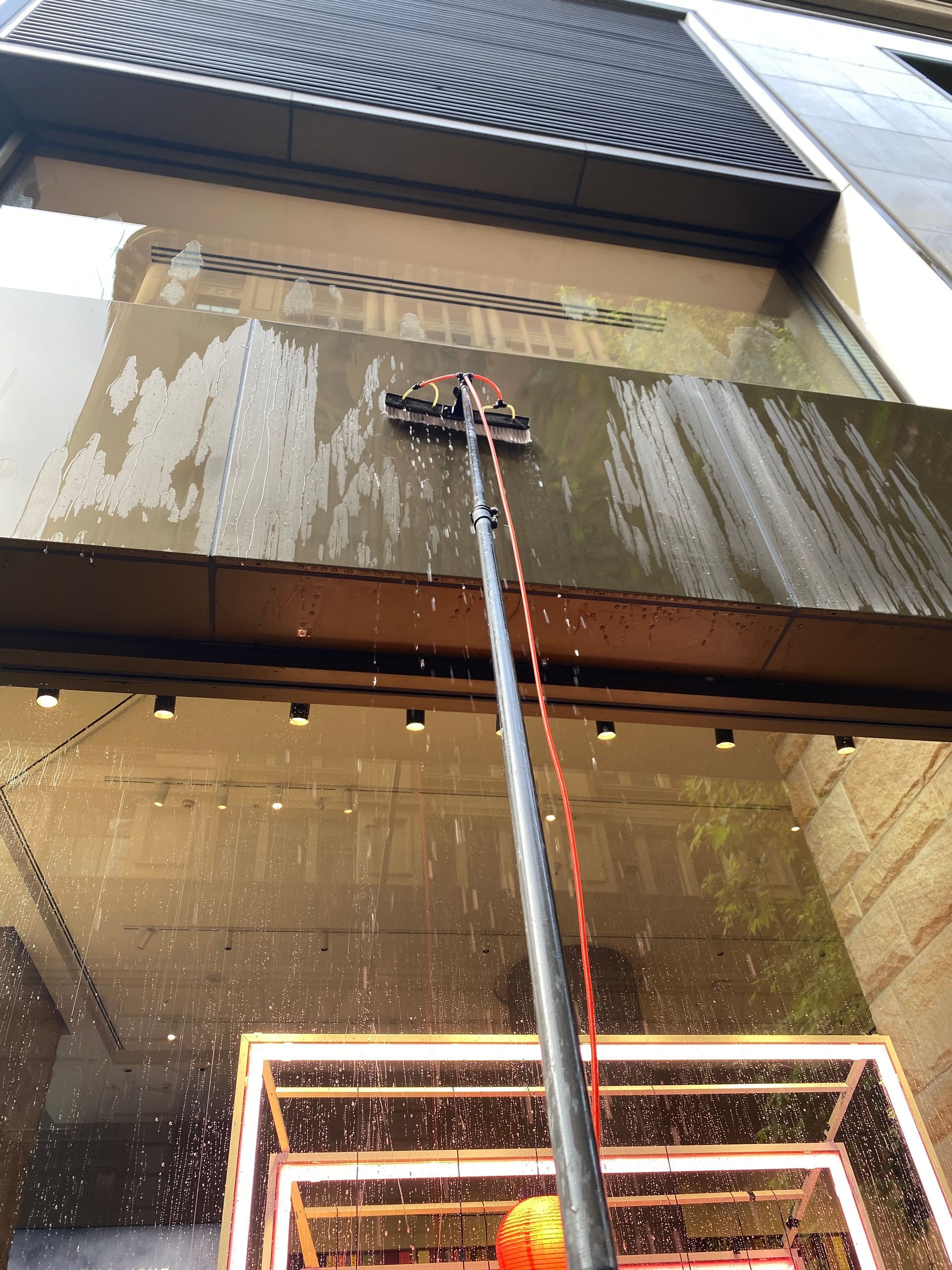 A Man Is Sitting On A Bucket Holding A Spray Bottle — Freshwater Exterior Cleaning in Lennox Head, NSW