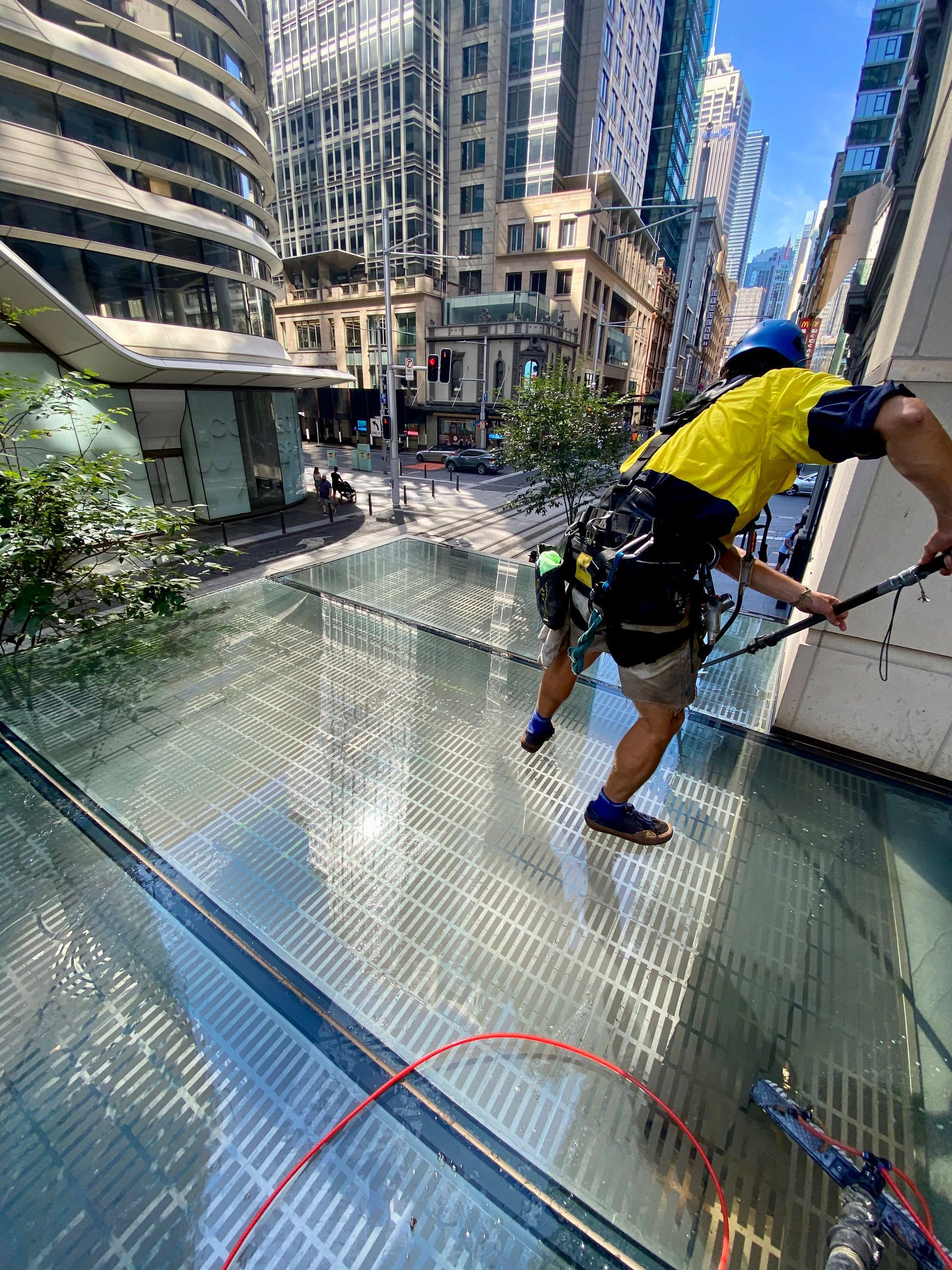 A Person Is Standing On A Glass Roof Cleaning It — Freshwater Exterior Cleaning in Lennox Head, NSW