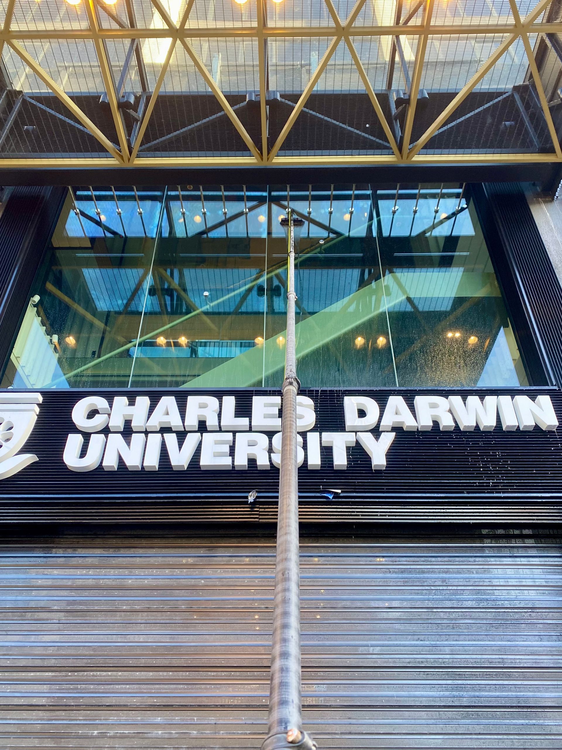 A Man Is Cleaning The Windows Of A Ray White Building — Freshwater Exterior Cleaning in Lennox Head, NSW