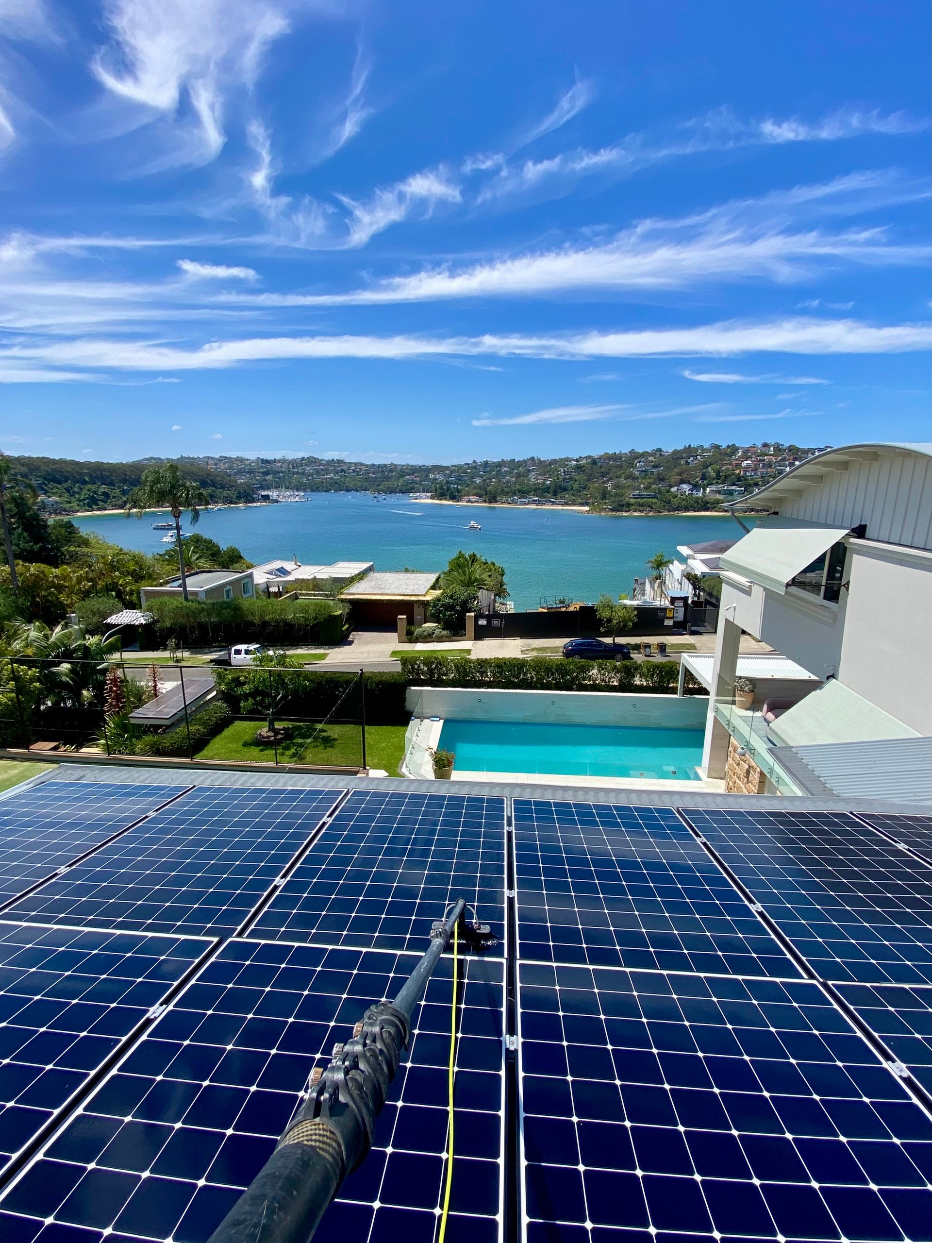 A Person Is Cleaning Solar Panels On The Roof Of A Building — Freshwater Exterior Cleaning in Lennox Head, NSW