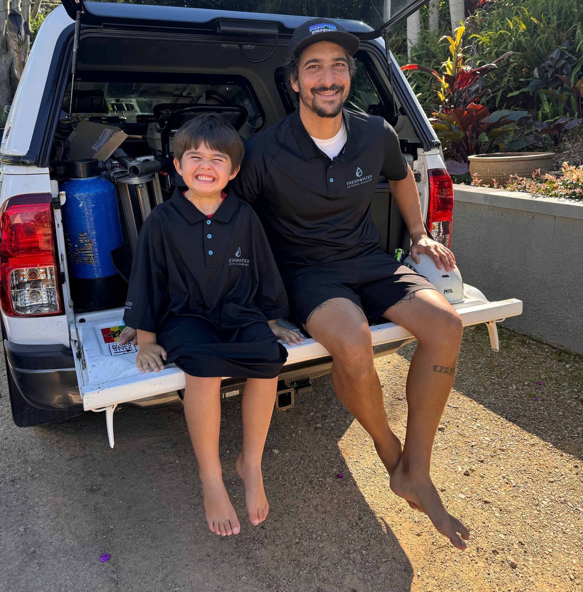Man with Son Sitting On End Of Ute In Cleaning Uniforms — Freshwater Exterior Cleaning in Lismore, NSW