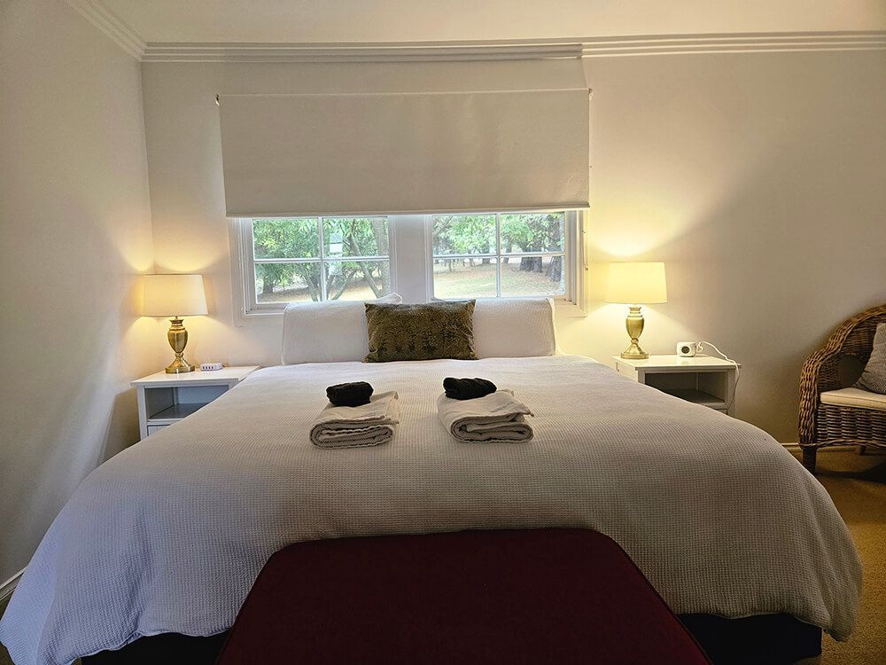 Bedroom with Queen Sized Bed With Two Lamps On Either Side And Half Open Window — A Perfect Move And Clean In Welby NSW