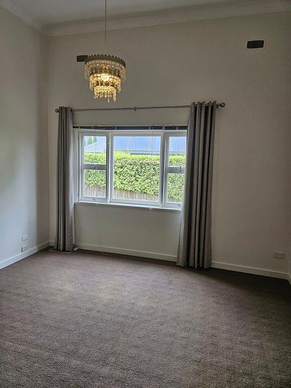 Spacious Bedroom with Chandelier Lights on Ceiling, Window with Open Curtains and Carpet Flooring — A Perfect Move And Clean In Moss Vale NSW