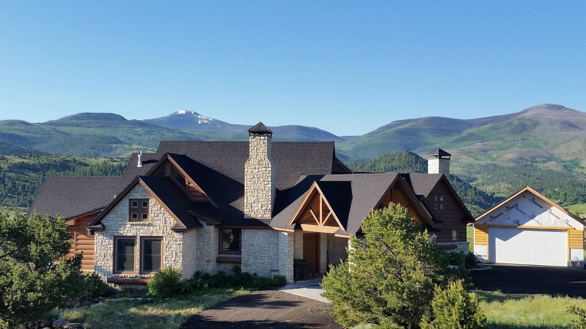 A large house in the middle of a field with mountains in the background