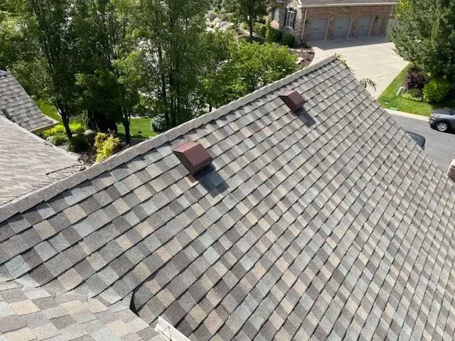 An aerial view of a roof with a lot of shingles and a house in the background.