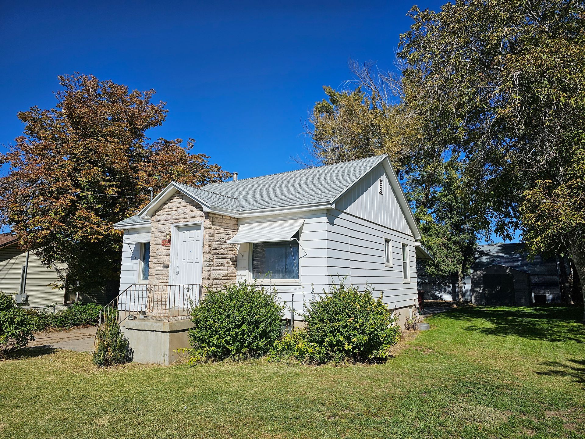 A small white house is sitting in the middle of a lush green field.