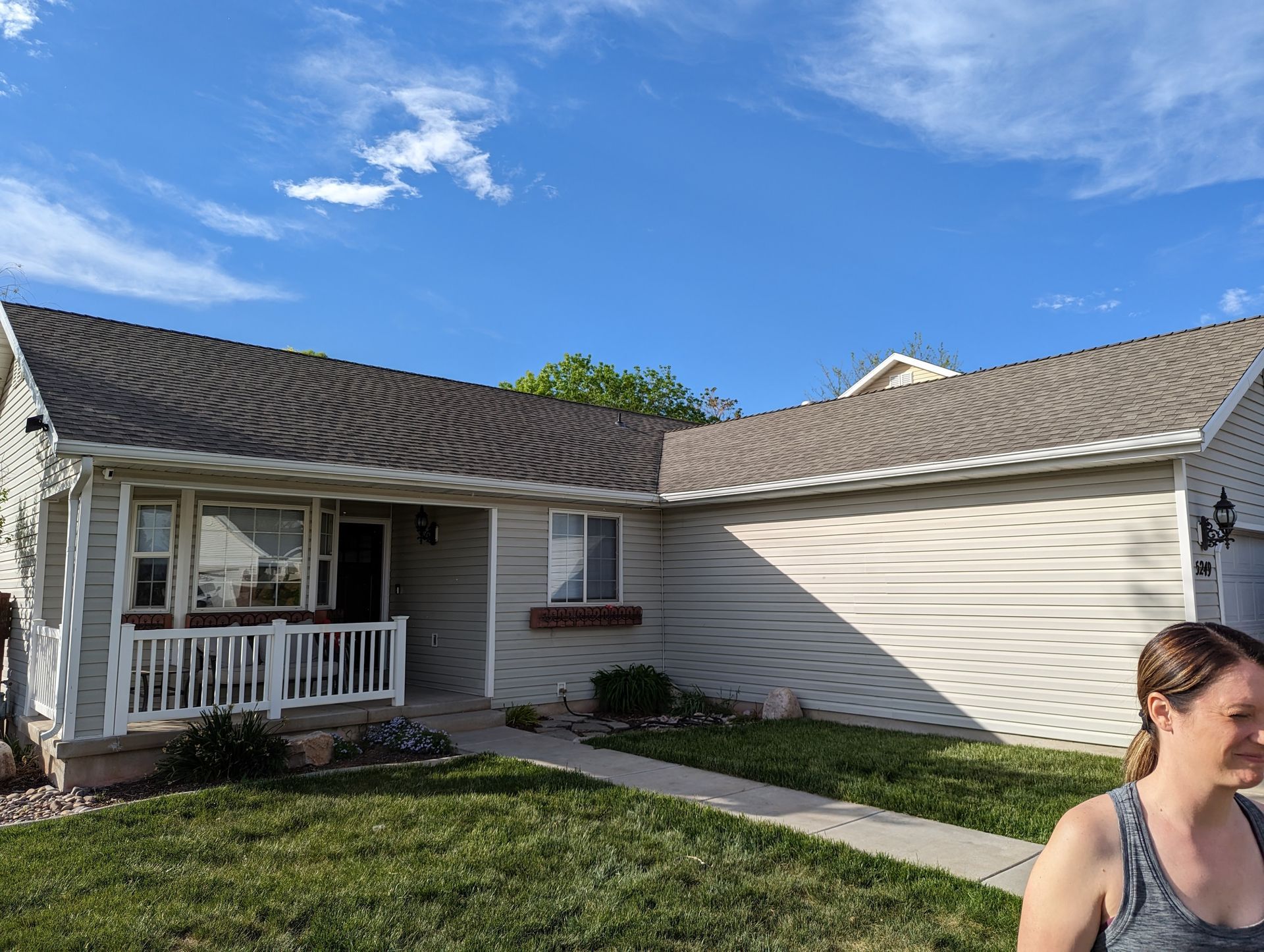 A woman is standing in front of a house on a sunny day.