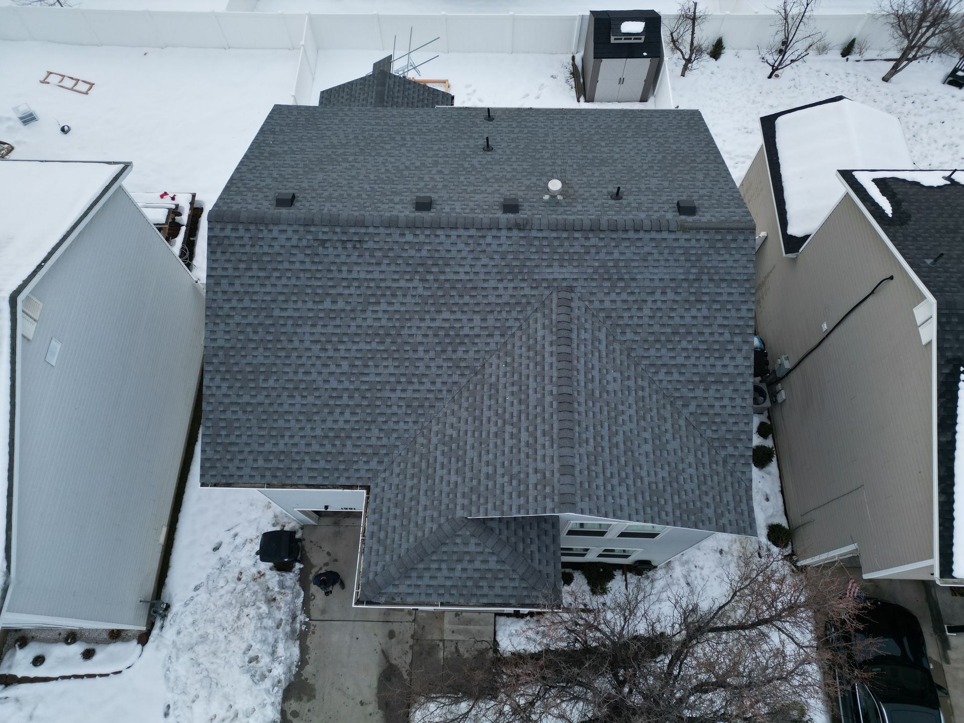 An aerial view of a house with a roof that is covered in snow.