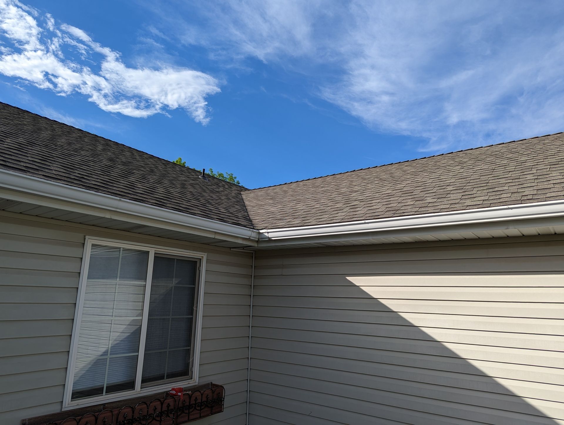 A house with a roof and a window with a blue sky in the background.
