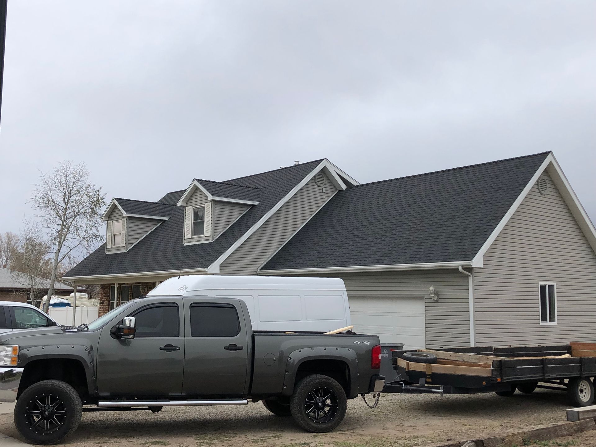 A truck with a trailer attached to it is parked in front of a house.