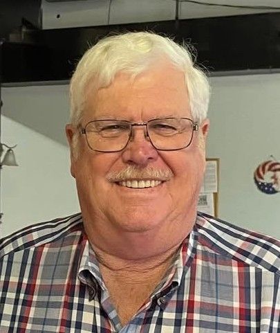 Woman wearing a burgundy beret, smiling and looking over her shoulder on a city street.